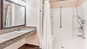Un baño con lavamanos doble, un espejo grande, ducha con puerta de vidrio y toallero.