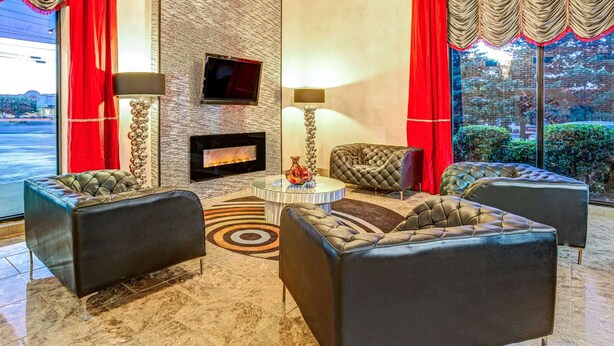 Un vestíbulo moderno con sofás de cuero, chimenea y un amplio ventanal con cortinas rojas.