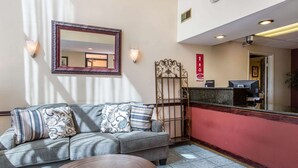 A reception area with a sofa, a round table, a mirror, and a reception desk. - Econo Lodge Inn & Suites Riverside - Corona (Riverside)