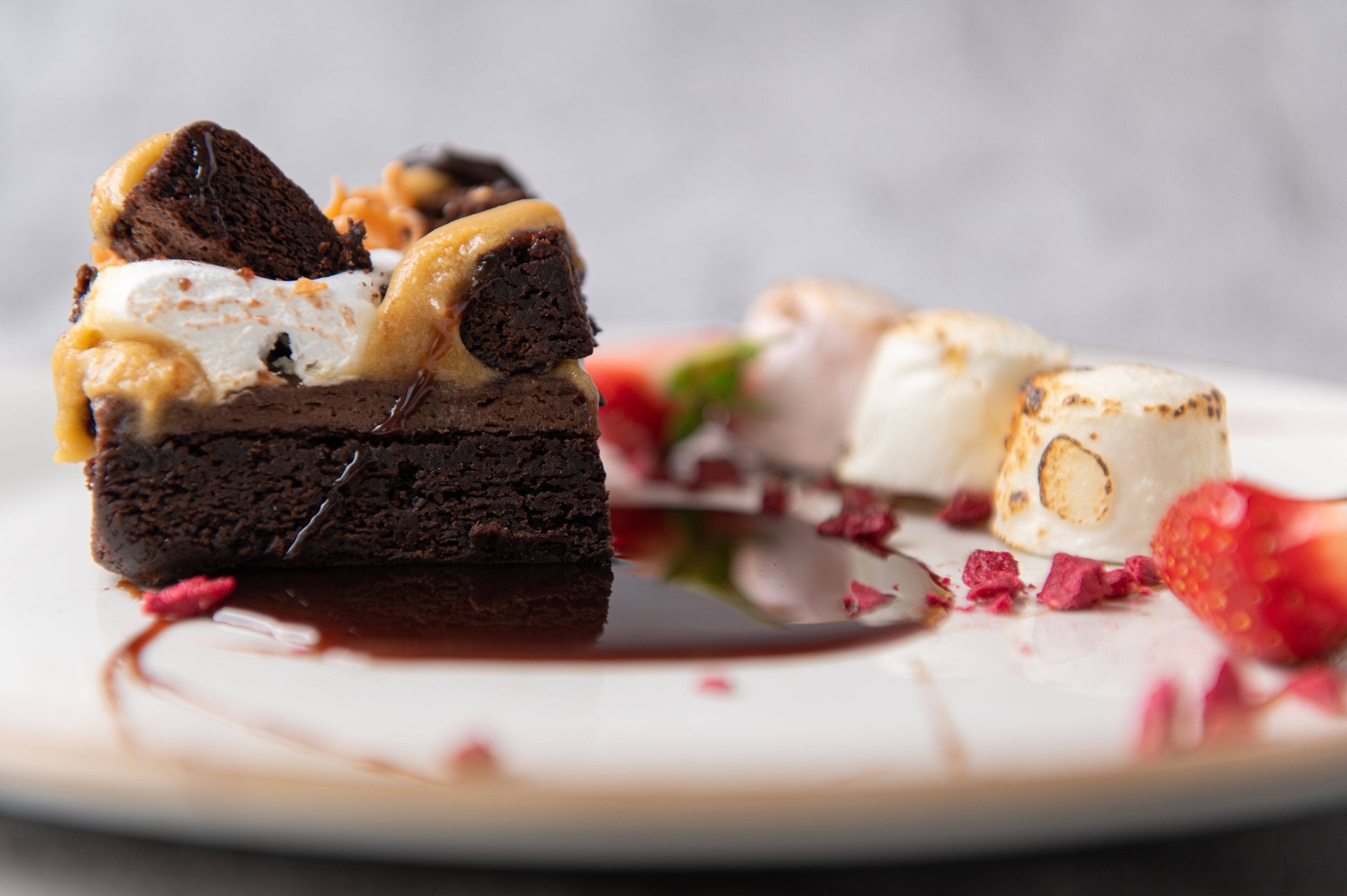 A dessert plate with a brownie, caramel, and a scoop of ice cream.