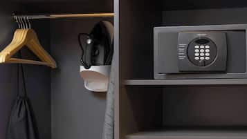 A hotel room with a wardrobe containing a hanging bag, a microwave, a kettle, and a coffee maker.