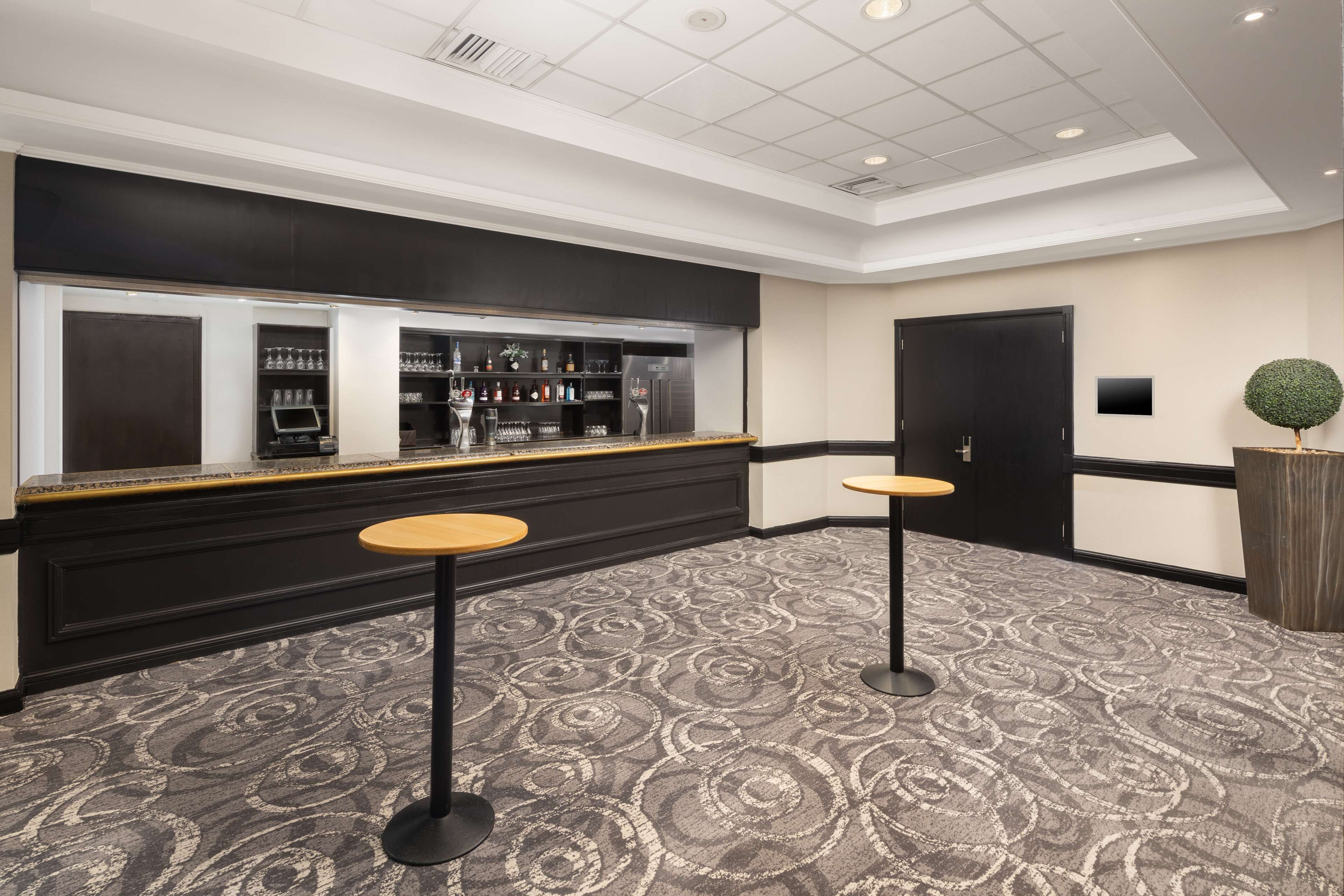 A bar area with a black counter, two stools, and a patterned carpet.