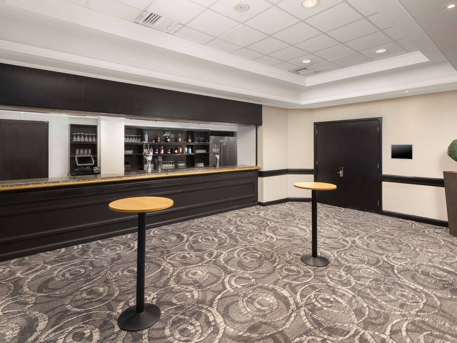 A bar area with a black counter, two stools, and a patterned carpet.