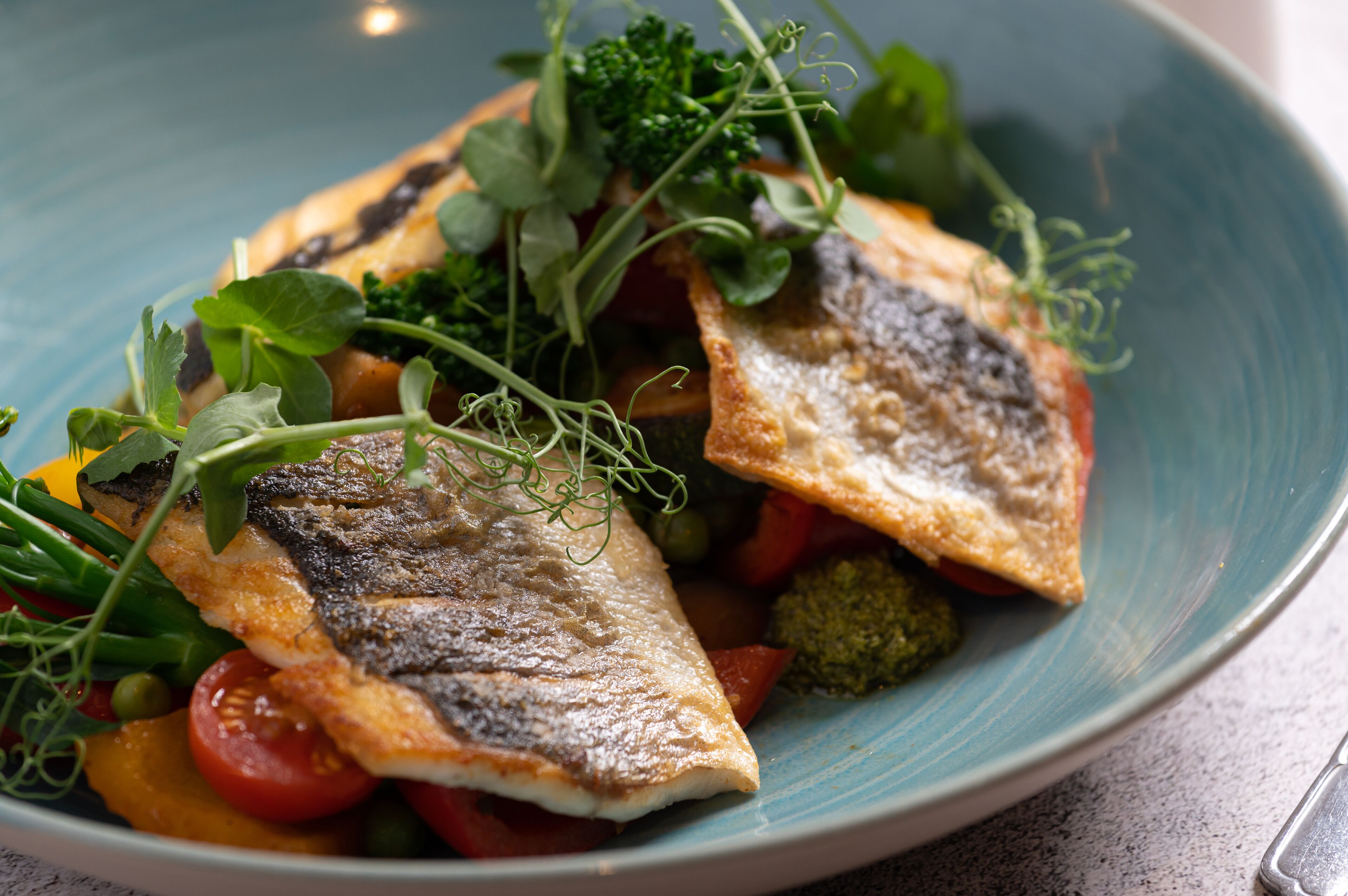 A plate of food with fish, vegetables, and greens.