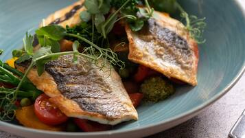 A plate of food with fish, vegetables, and greens.