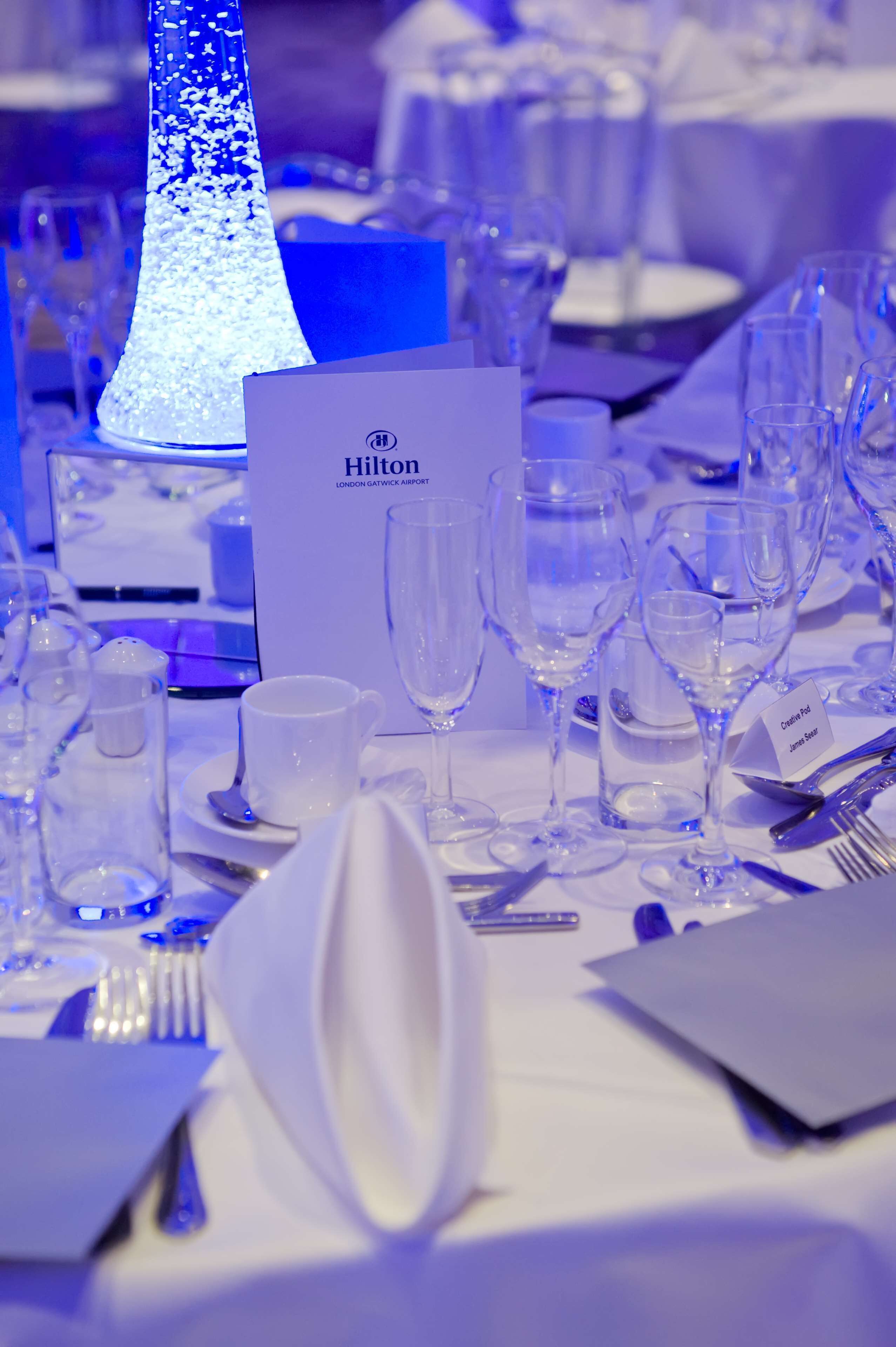 A table set for a meal with a lit centerpiece, a menu card, and empty glassware.