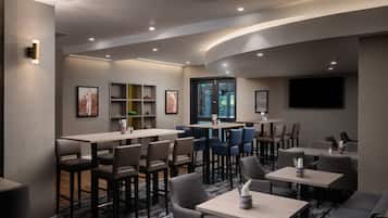 A modern restaurant with high tables and chairs, a flat-screen TV, and framed artwork on the walls.