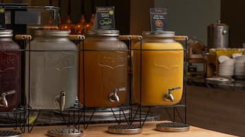 A beverage station with various drink dispensers, including a green tea and an orange juice option.