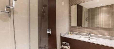 A modern bathroom with a glass-enclosed shower, a separate toilet, and a vanity with a sink and mirror.