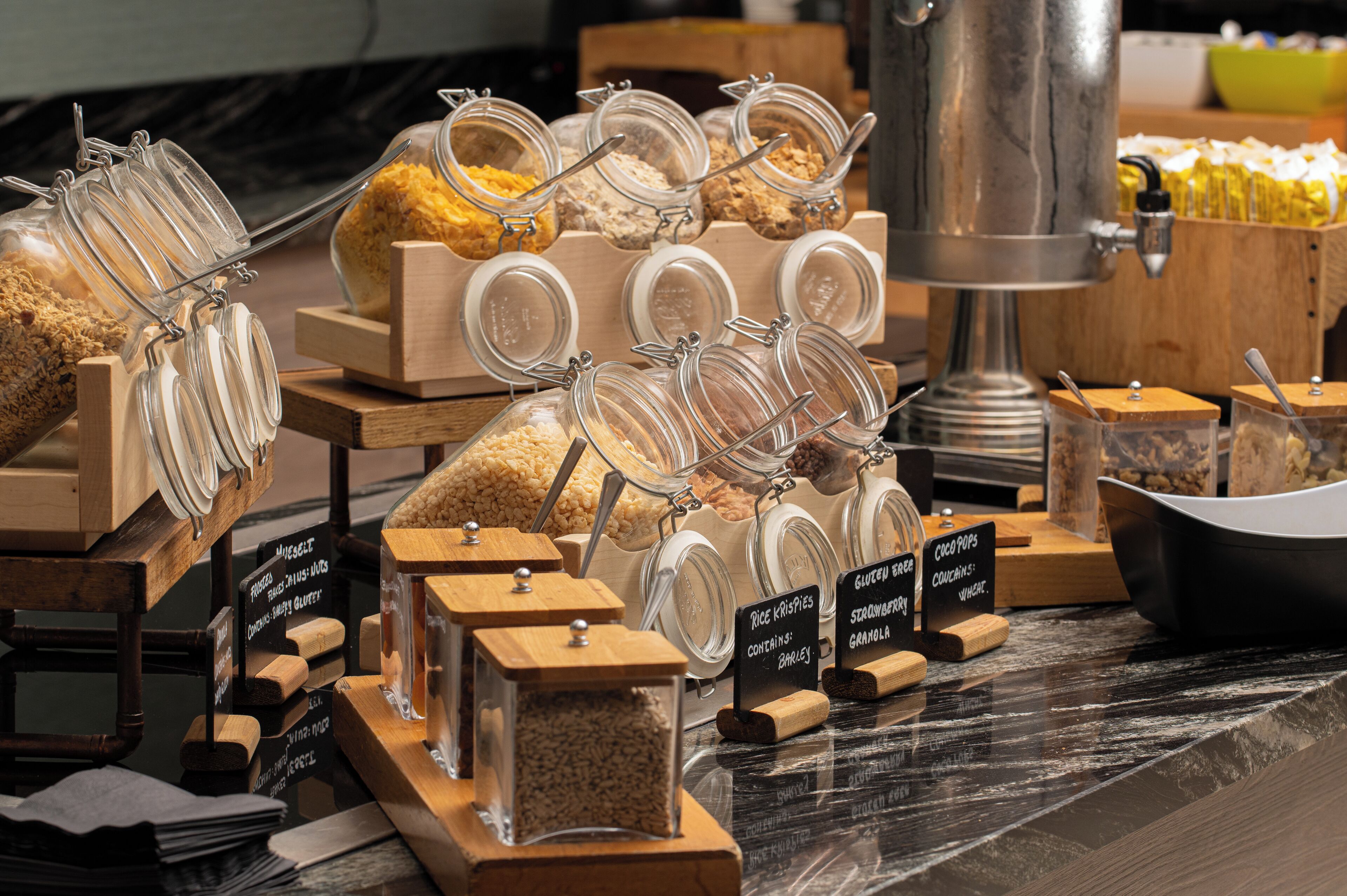 A buffet with various food items in glass containers, including rice, granola, and cereal.
