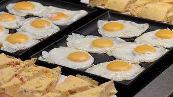 A breakfast tray with fried eggs and a variety of pastries.