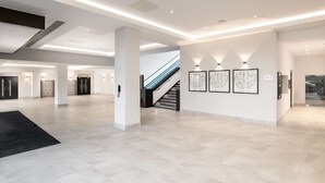 A spacious lobby with a staircase, modern lighting, and artwork on the walls.