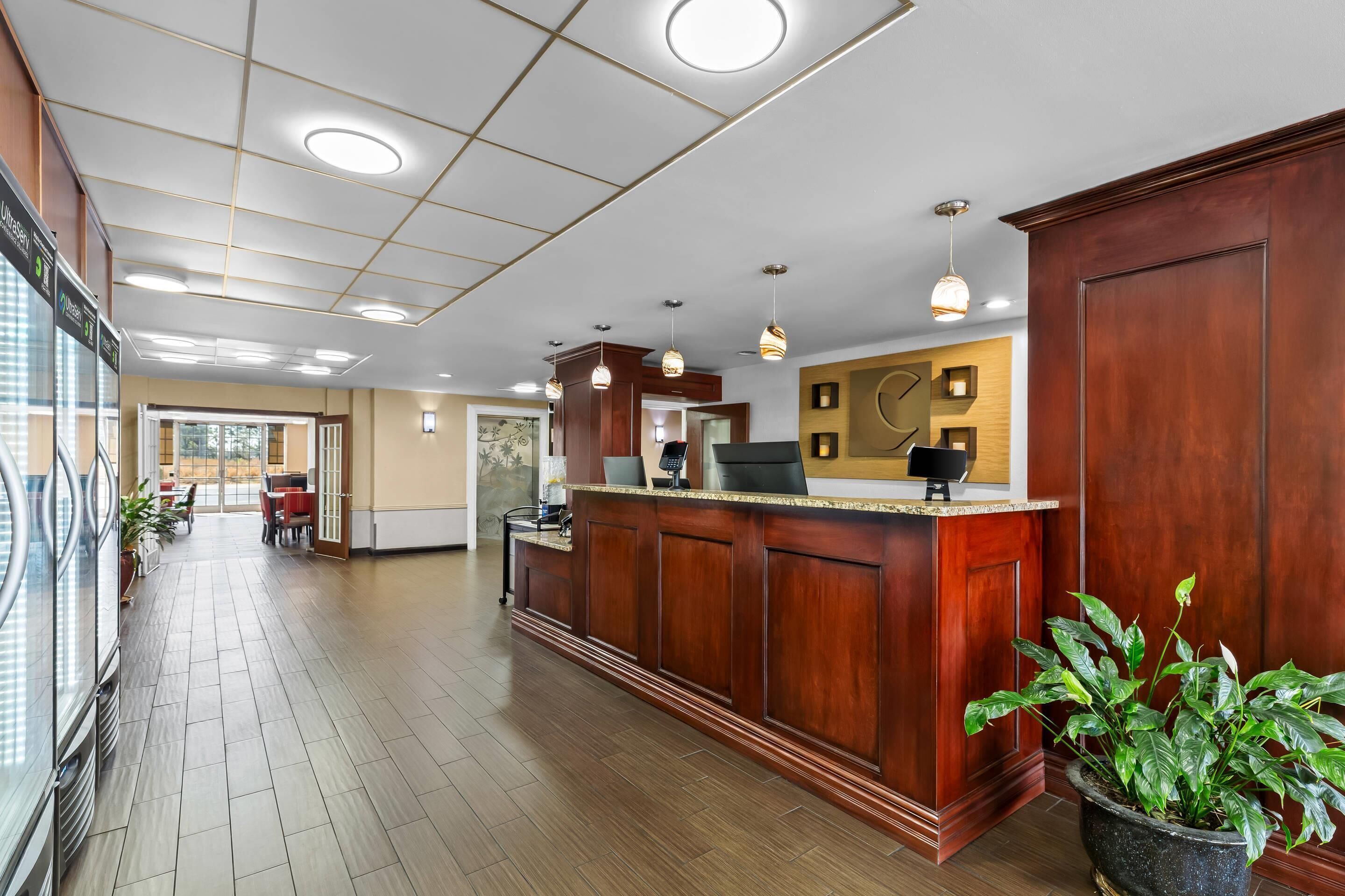 A reception area with a wooden reception desk, a potted plant, and a view of the outdoor area.