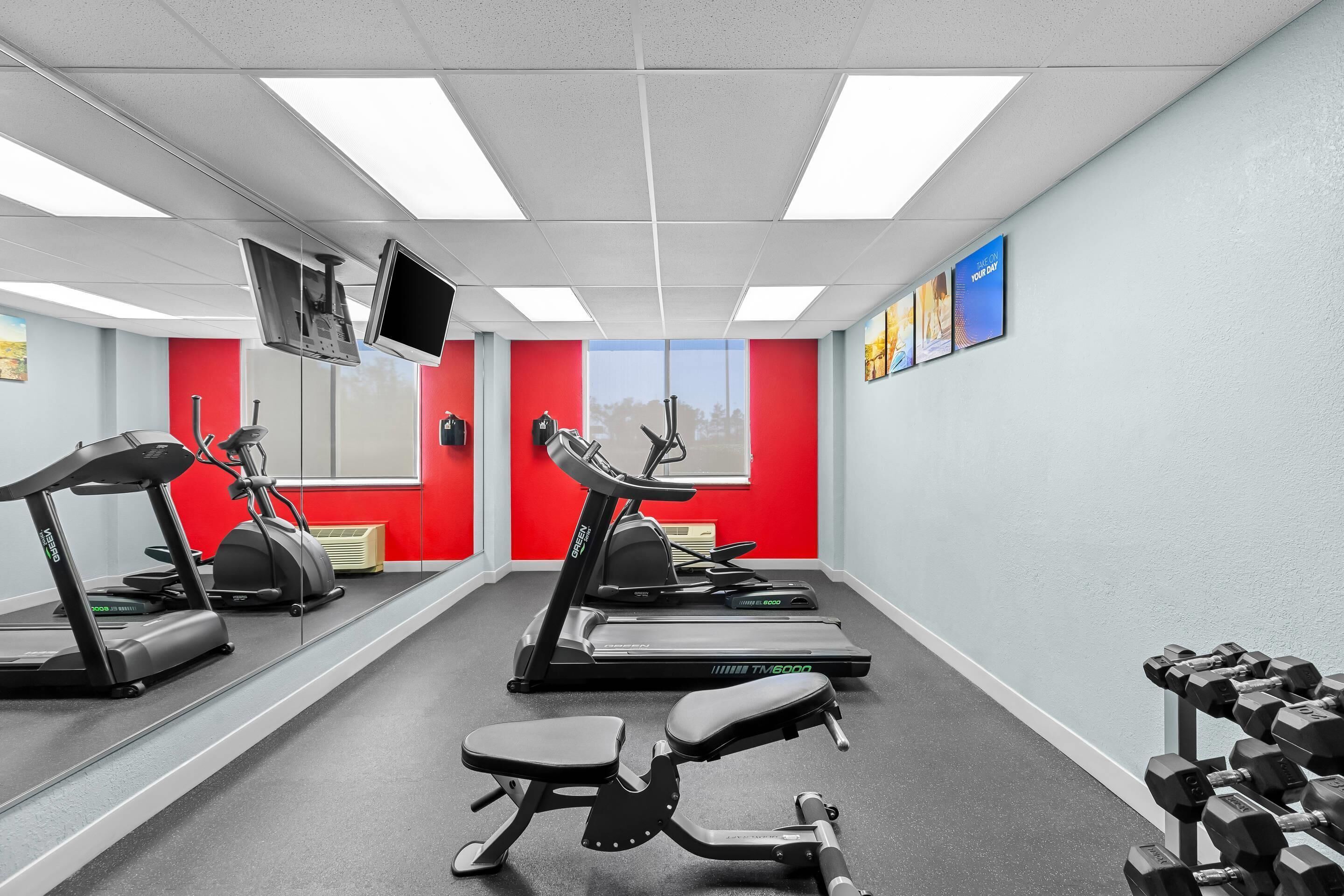 A gym with treadmills, a stationary bike, a rowing machine, and dumbbells.