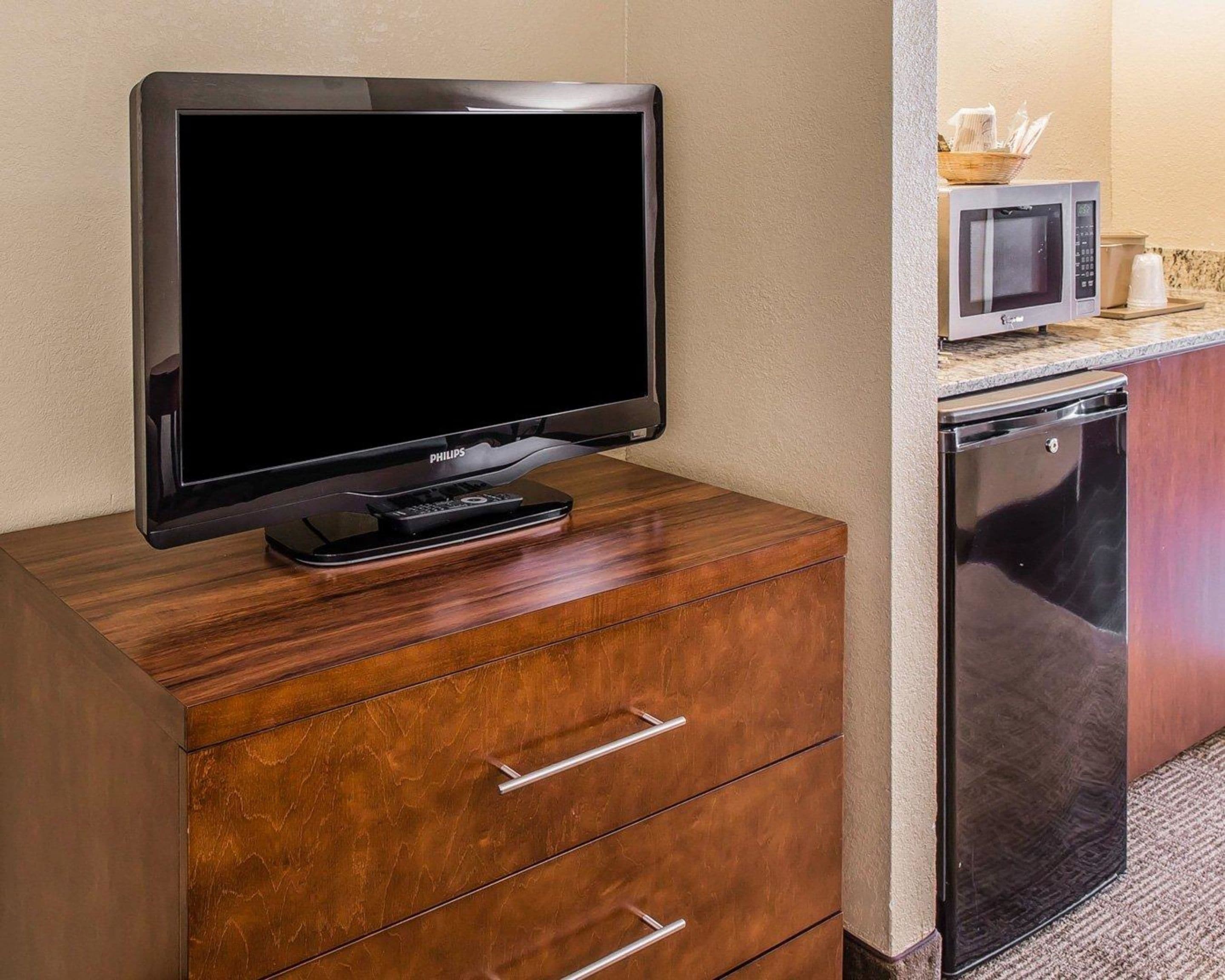 Una televisione su un mobile in legno, un forno a microonde e una lavastoviglie in una zona cucina.