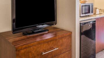 Un téléviseur posé sur un meuble en bois, un four à micro-ondes et un lave-vaisselle dans un coin cuisine.