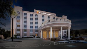 A hotel with a central entrance, multiple floors, and a sign reading 'Comfort Inn & Suites.'