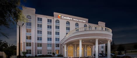 A hotel with a central entrance, multiple floors, and a sign reading 'Comfort Inn & Suites.'