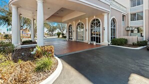 A hotel entrance with a covered walkway, columns, and arched windows.