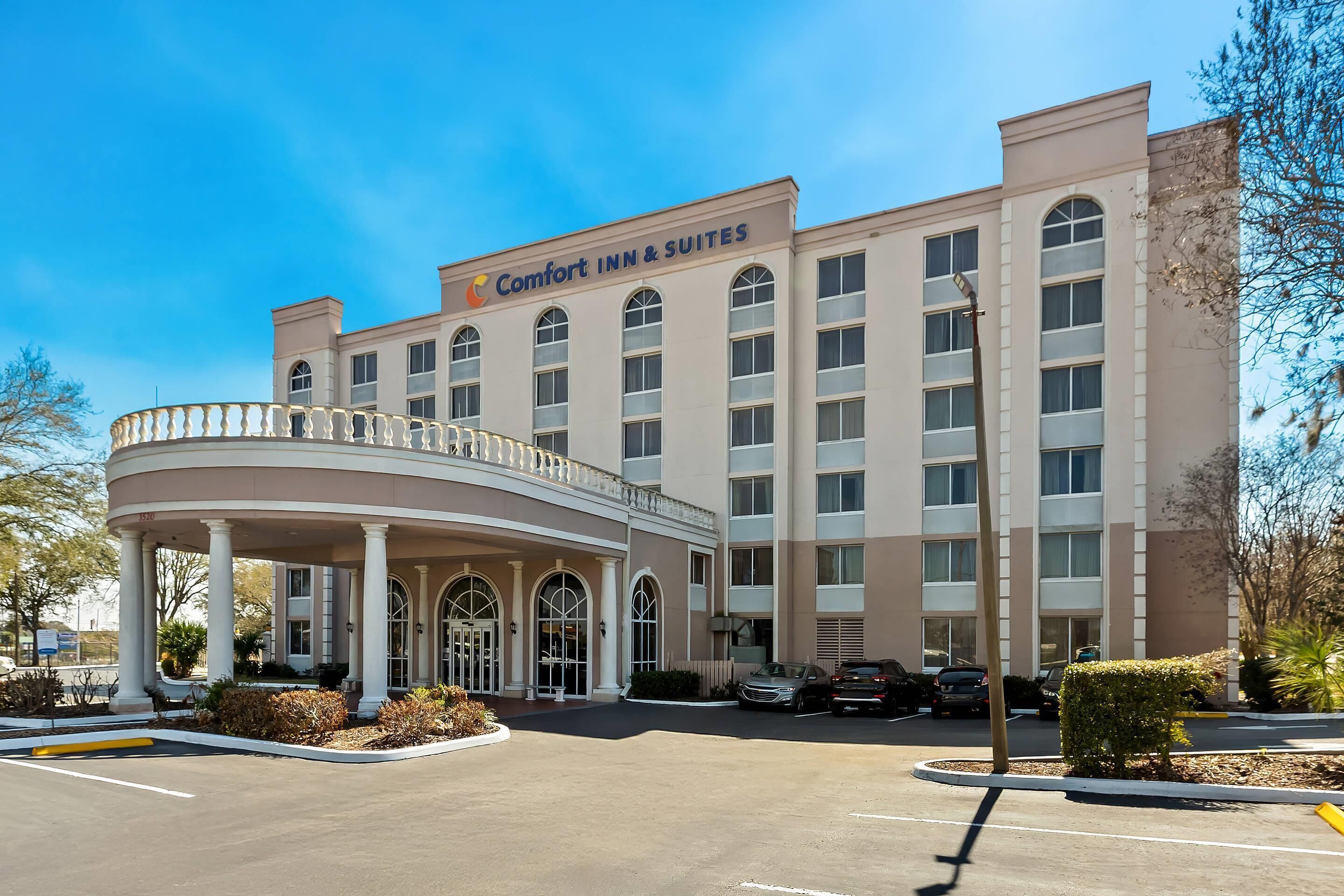 A hotel with a central entrance, a covered area with columns, and a sign reading 'Comfort Inn & Suites'.