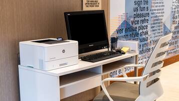 A workspace with a desktop computer, a printer, and a chair.
