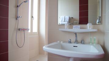A bathroom with a shower, sink, and mirror.