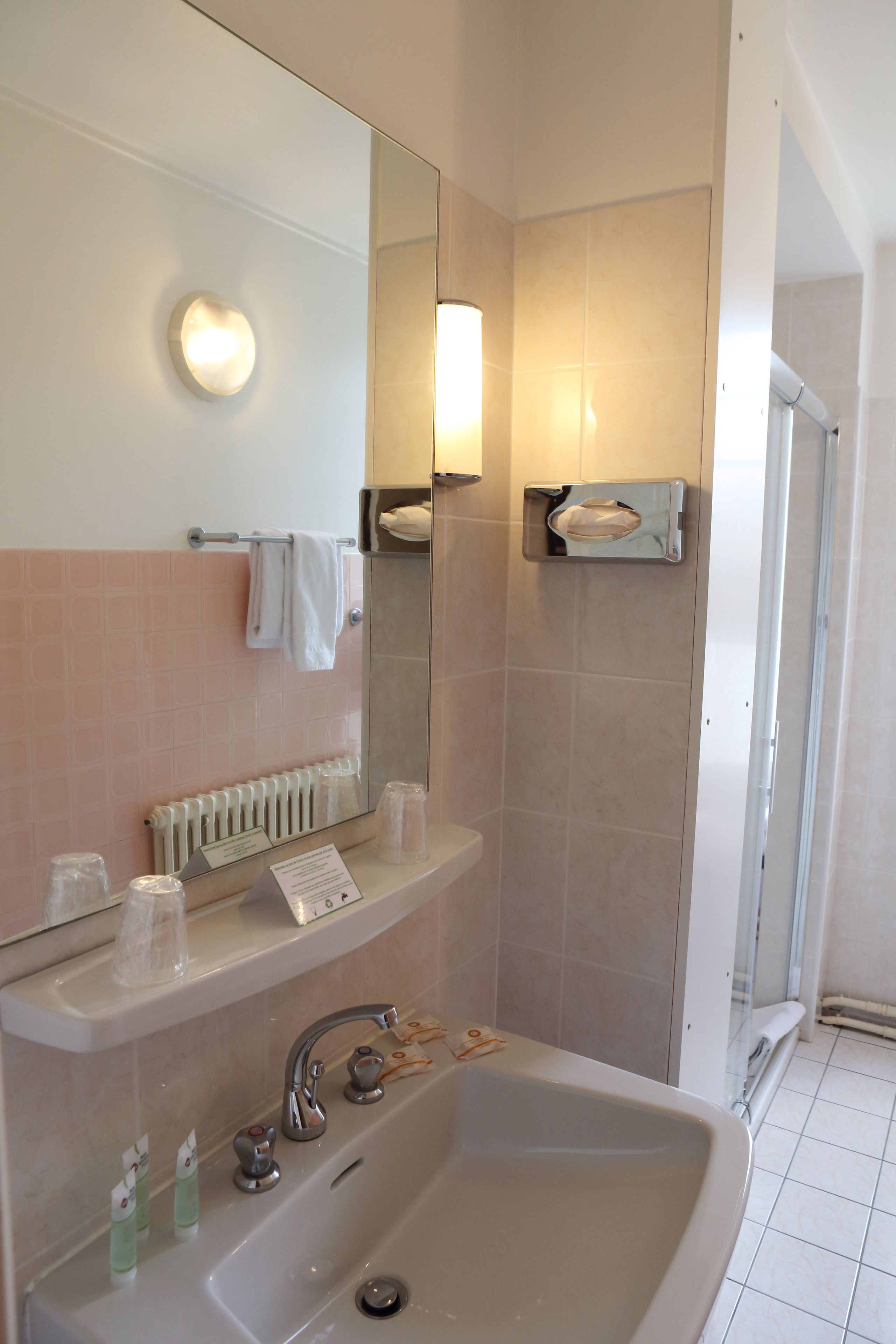 A bathroom with a sink, mirror, towel rack, and a glass shower door.