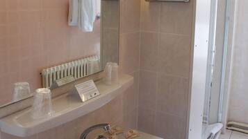 A bathroom with a sink, mirror, towel rack, and a glass shower door.