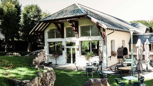 A two-story house with a sloped roof, large windows, and a patio area with outdoor furniture. - Best Western Grand Hotel de Paris & Spa (Villard-de-Lans)