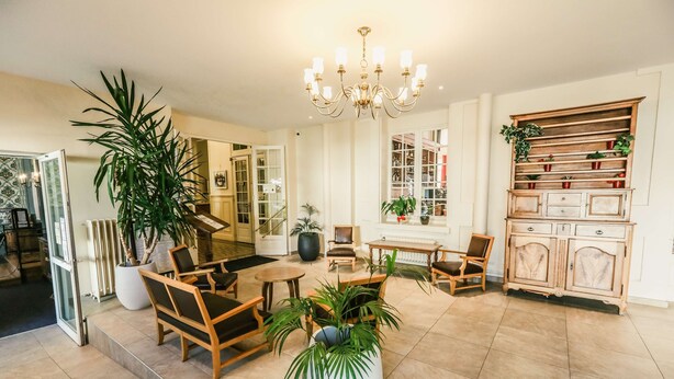 A spacious lobby with a chandelier, wooden furniture, and potted plants. - Best Western Grand Hotel de Paris & Spa (Villard-de-Lans)
