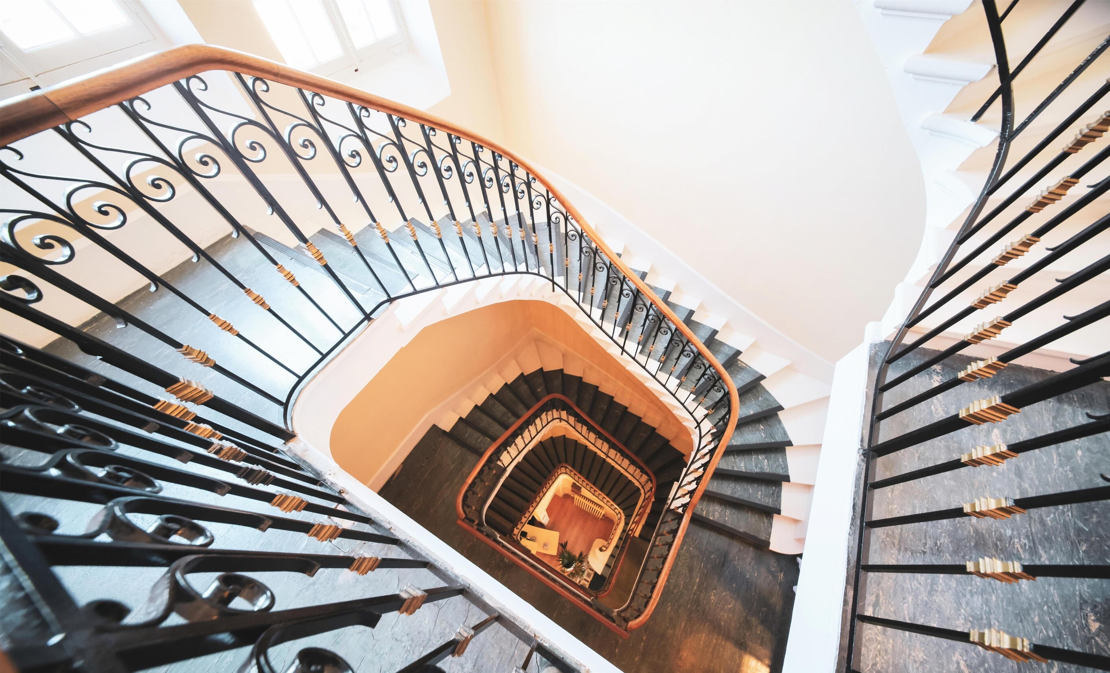A spiral staircase with ornate black railings and wooden handrails.