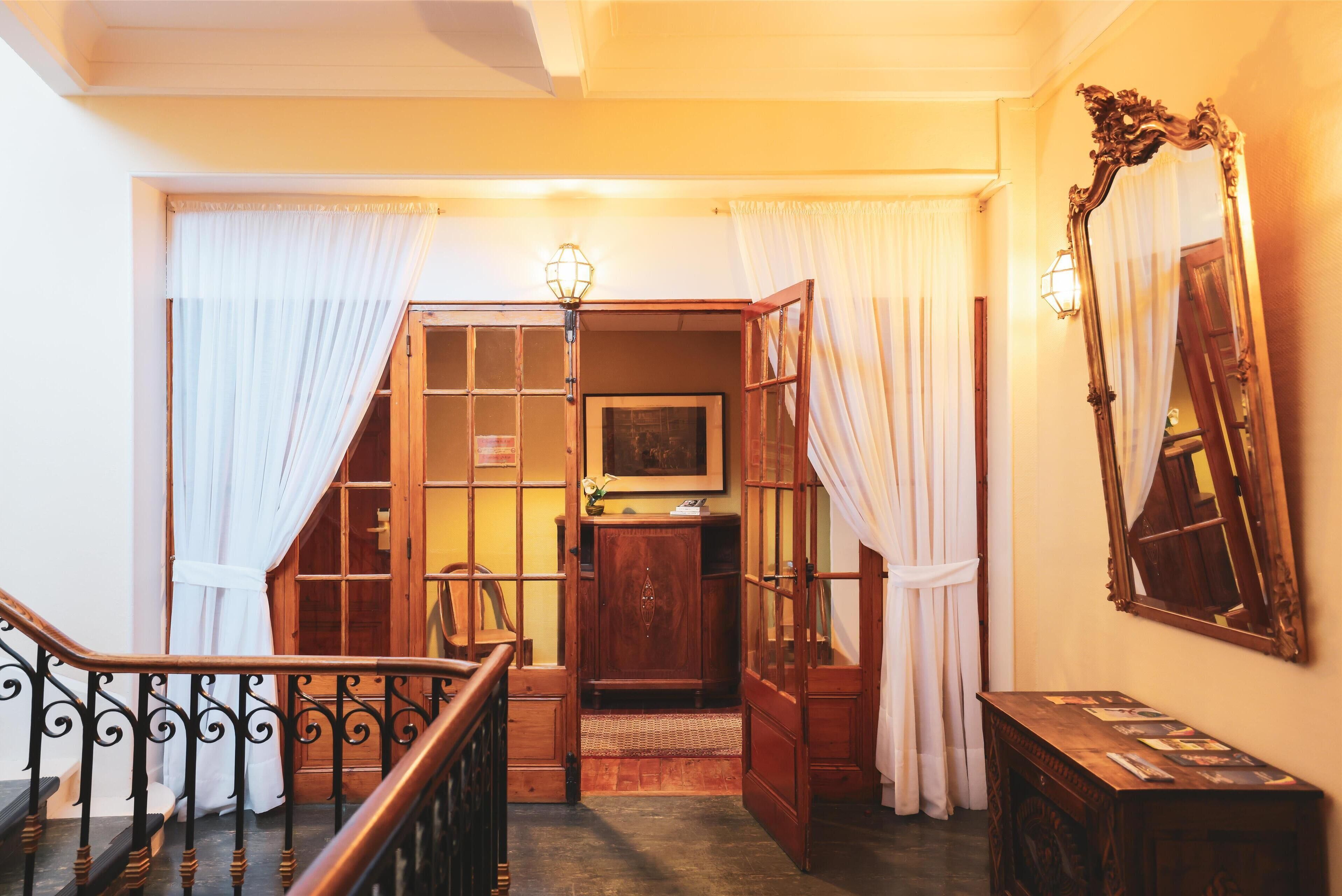 A staircase with a wooden railing, a wooden door, and a wall-mounted mirror.