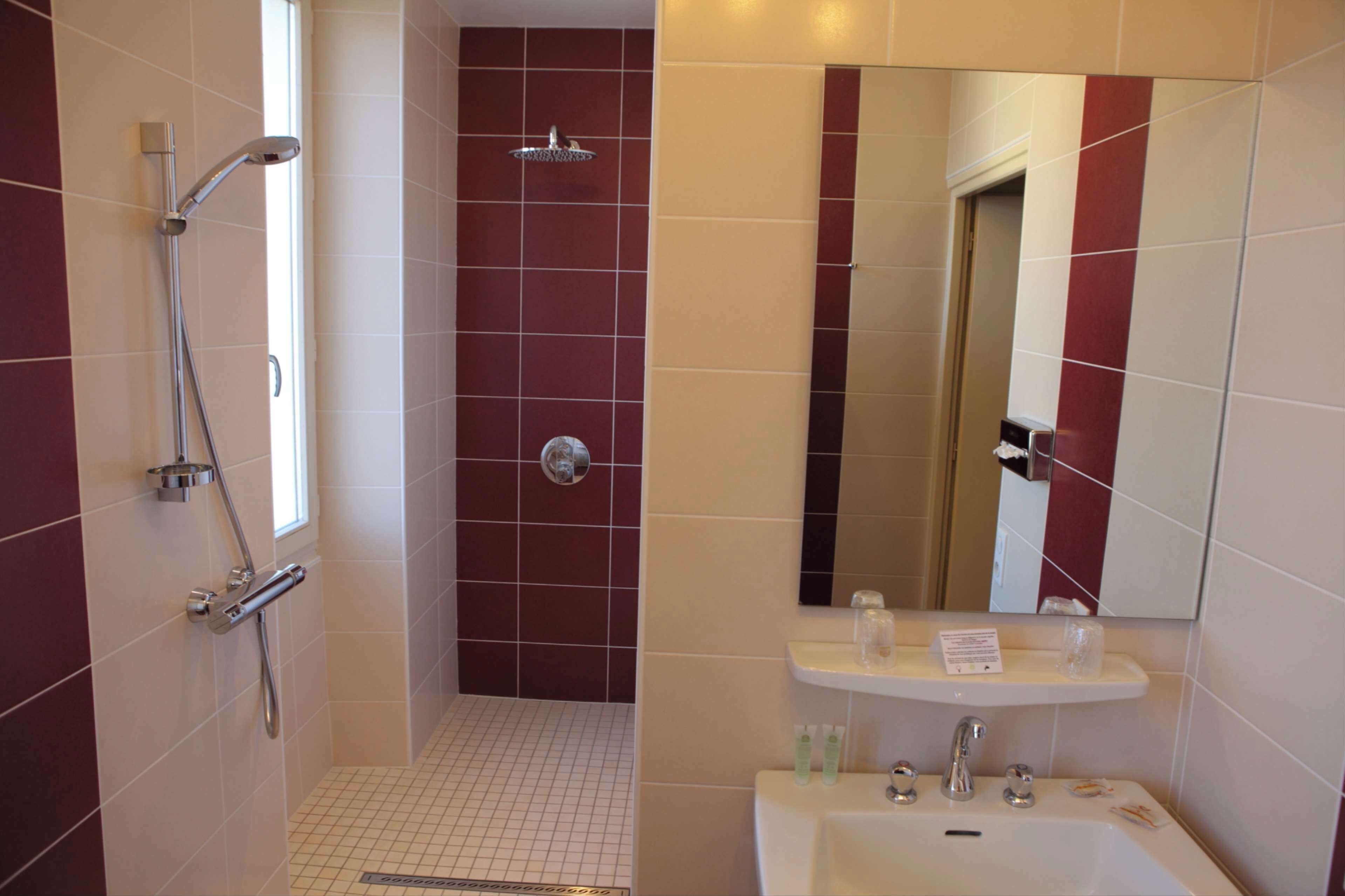 Un baño con ducha, lavamanos y espejo.