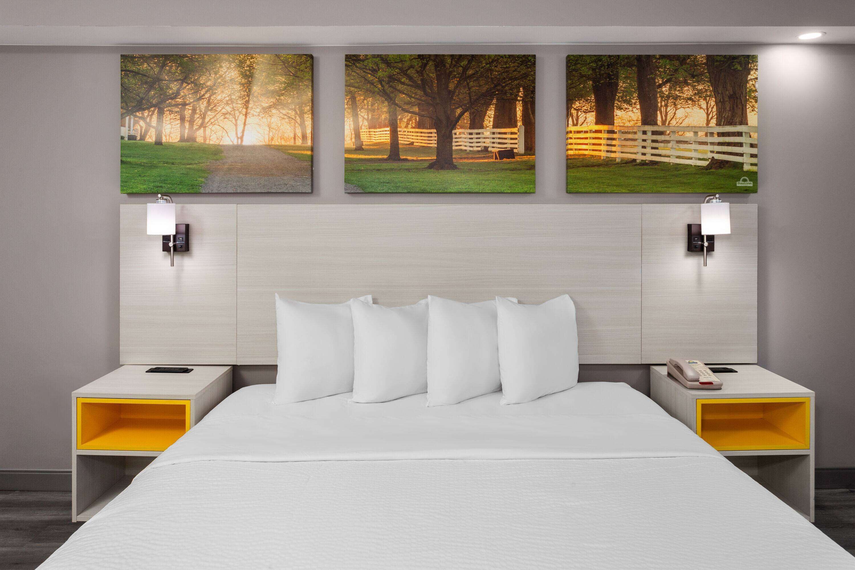 A hotel room with a large bed, two bedside tables with lamps, and three framed pictures on the wall.