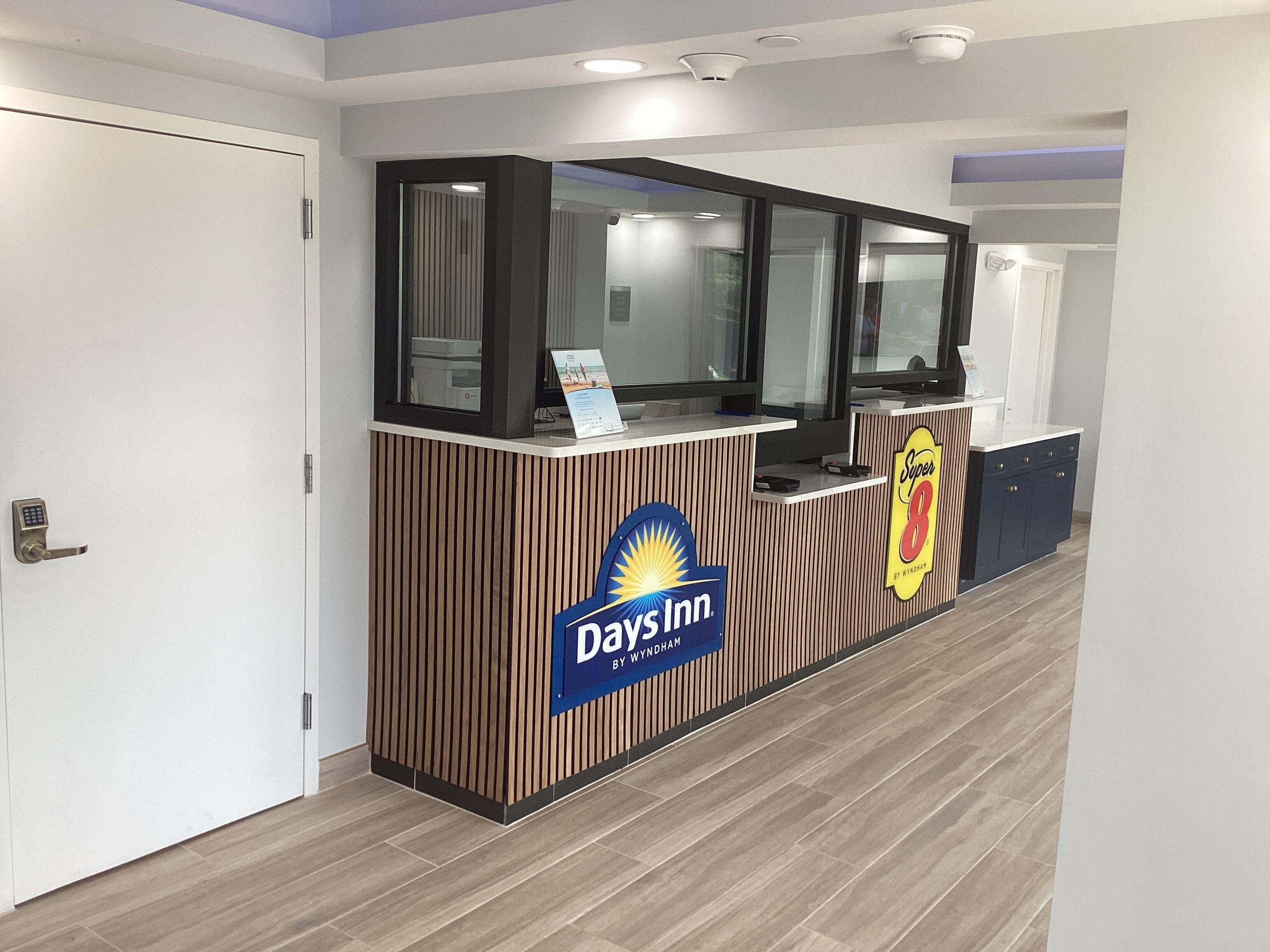 A reception desk with a 'Days Inn' sign, a security keypad, and a 'Super 8' sign.