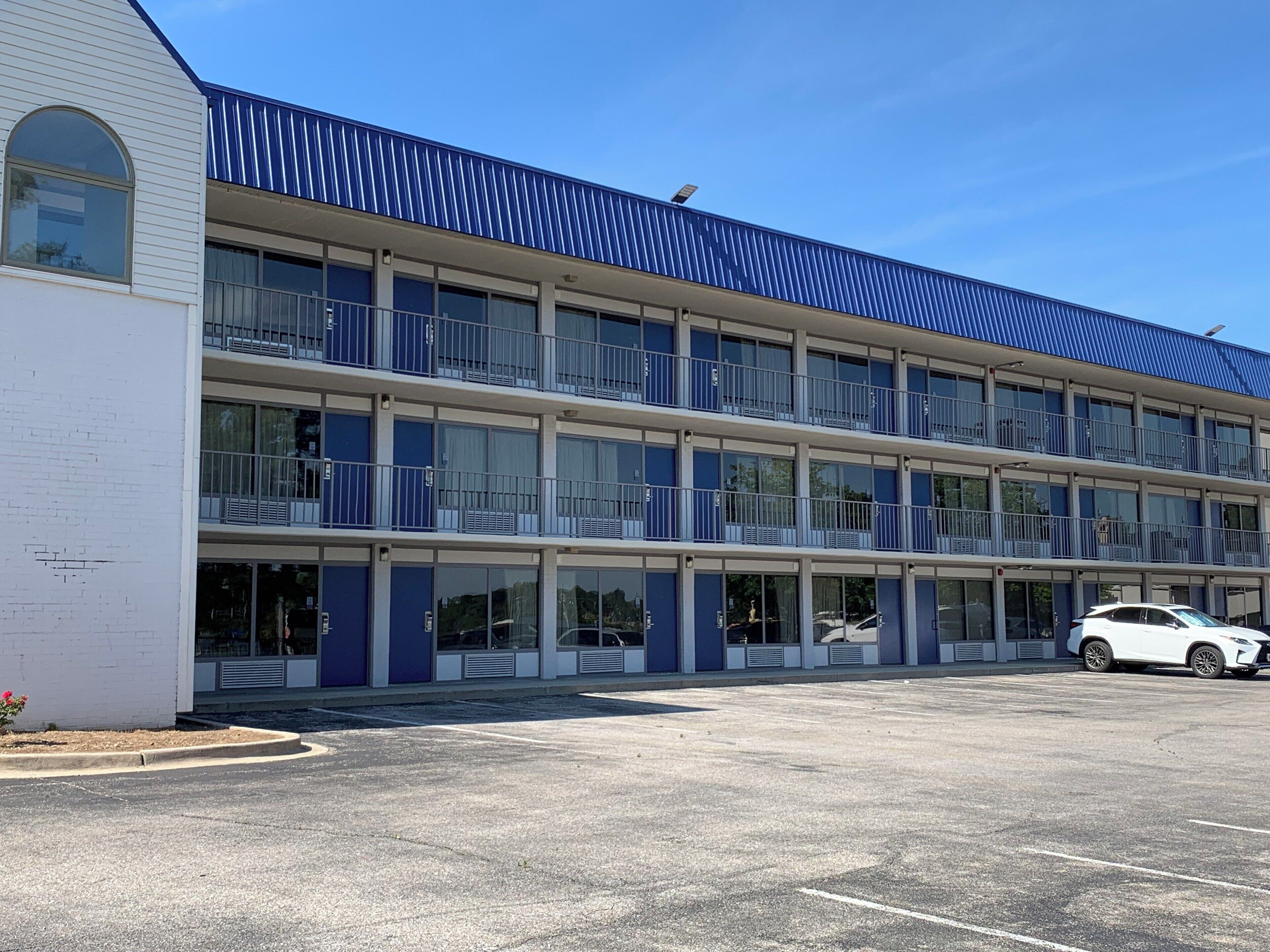 A multi-story motel with a blue roof and white exterior walls.