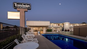 A Travelodge by Wyndham with a swimming pool, outdoor seating, and a well-lit entrance. - Travelodge by Wyndham Page, View of Lake Powell (Page)
