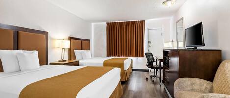 A hotel room with two beds, a desk, a television, and a seating area.