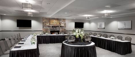 A conference room with a long table, chairs, a fireplace, and artwork on the walls.