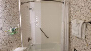 Un baño con ducha, bañera, toallero y estante con artículos de aseo.