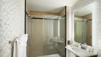 A modern bathroom with a glass-enclosed shower, a white sink, and a mirror.