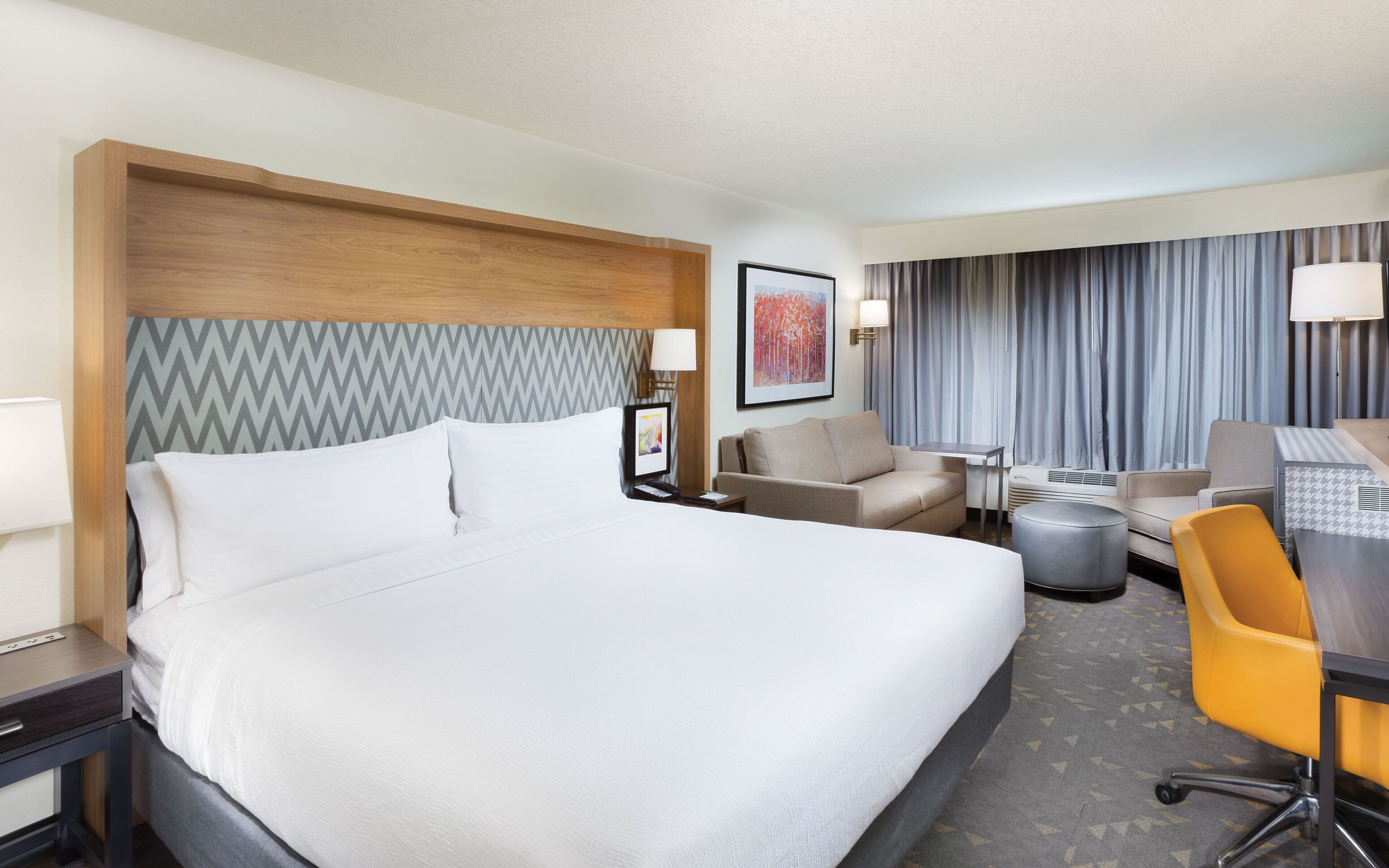 Een hotelkamer met een groot bed, een bank, een bureau en een stoel.