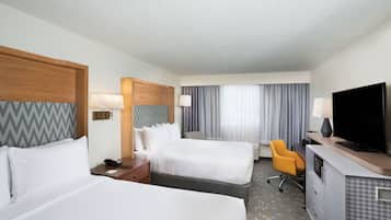 Une chambre d’hôtel avec deux lits, un bureau, une télévision et une chaise.