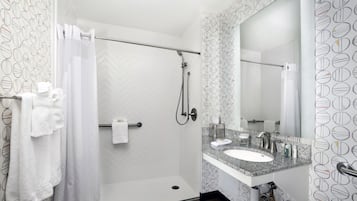 Une salle de bain moderne équipée d’une douche, d’un lavabo et d’un miroir.