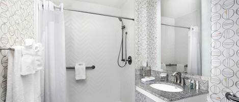 Un baño moderno con ducha, lavabo y espejo.