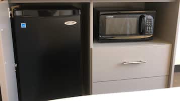 Un refrigerador negro y un microondas negro sobre un mueble gris.