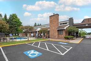 A parking lot with handicapped parking spaces, a brick building, and a pool area.