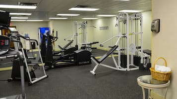 Ein Fitnessstudio mit unterschiedlichen Trainingsgeräten, darunter Laufbänder, Kraftgeräte und ein Wand-Kabelzuggerät.