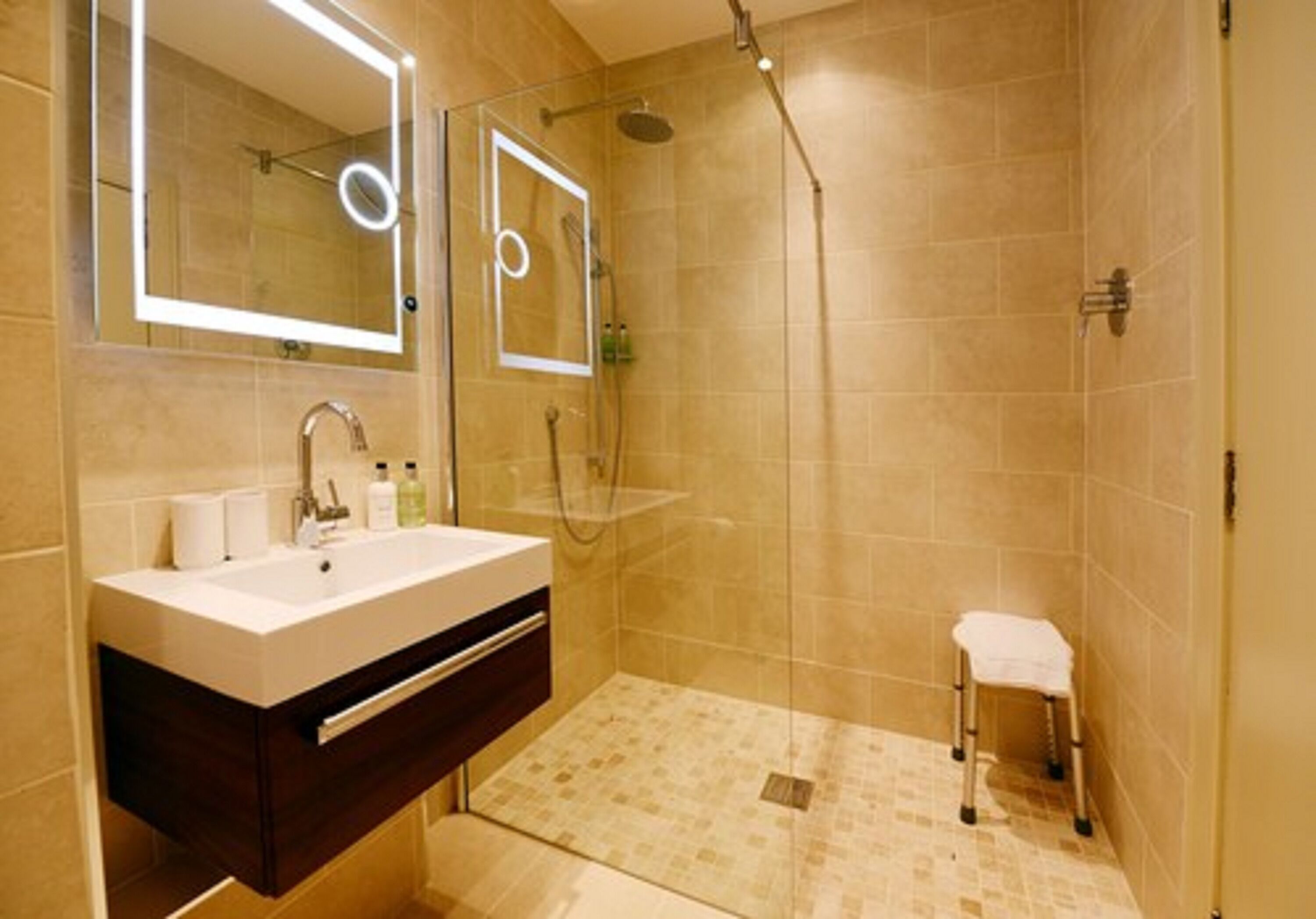 Un baño moderno con un espejo grande, un lavamanos y una zona de ducha.