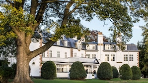 A large, stately building with a symmetrical facade, multiple windows, and a well-maintained lawn with neatly trimmed hedges. - The Ripon Inn - The Inn Collection Group (Ripon)